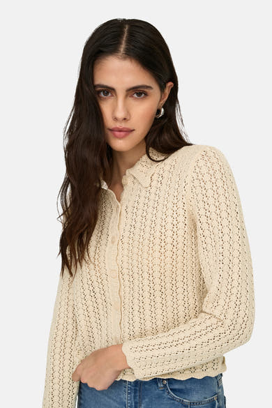 Cardigan écru de JDY, en maille ajourée à manches longues, porté sur un jean.