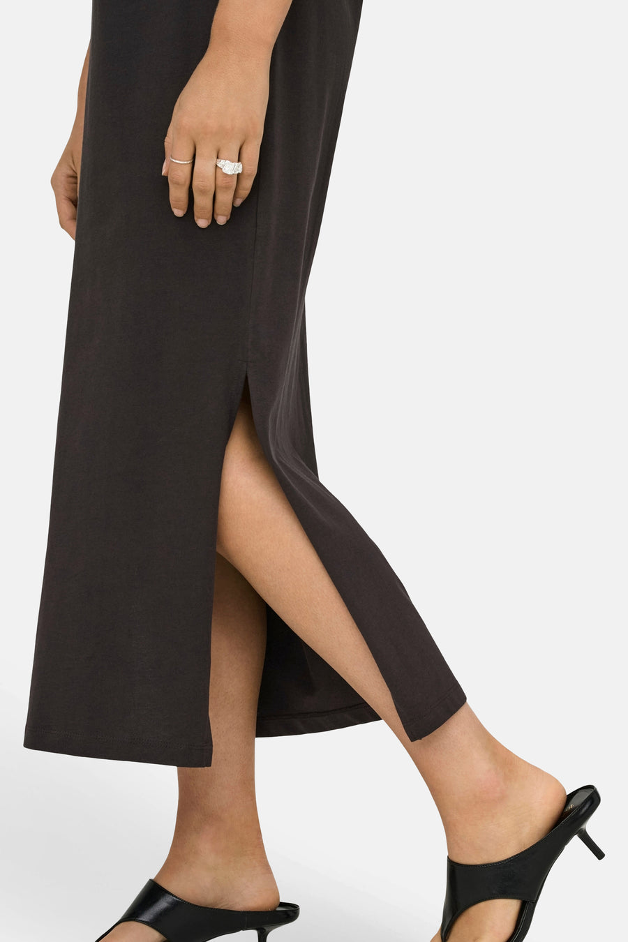 Robe marron de ONLY, fendue sur le côté, portée avec des mules noires à talons aiguilles et des bagues argentées.
