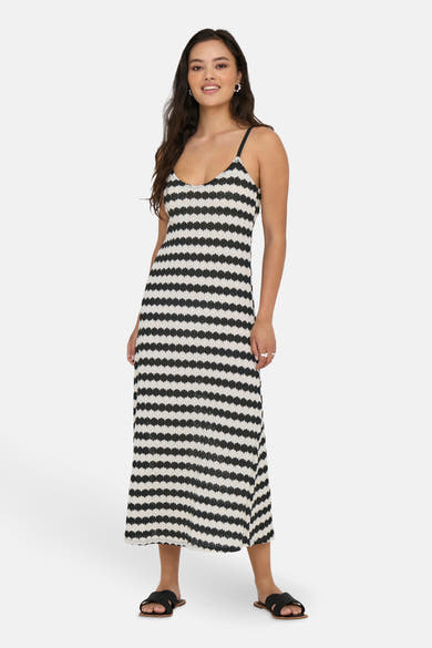 Zwarte lange jurk met strepen, van ONLY®, gedragen met gevlochten platte sandalen.