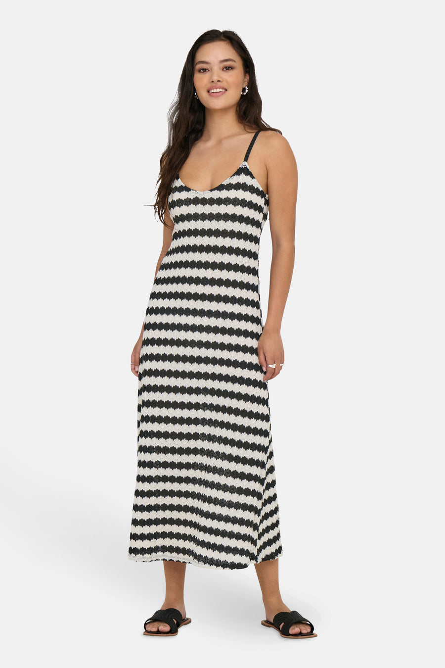 Zwarte lange jurk met strepen, van ONLY®, gedragen met gevlochten platte sandalen.