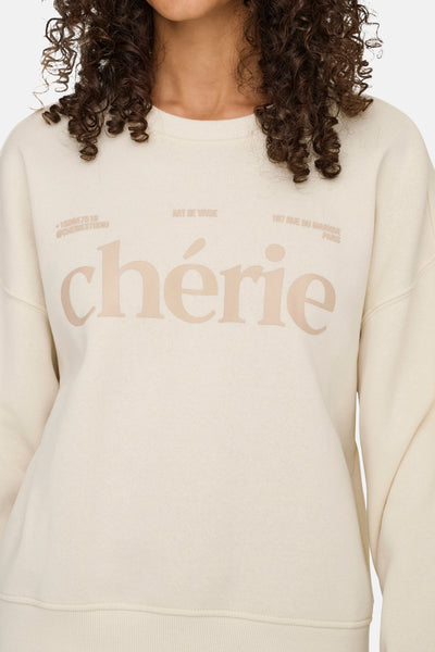 Sweat beige col rond de ONLY®, avec lettrage décoratif "chérie" et inscriptions textuelles.