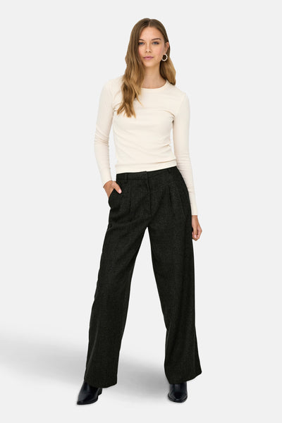 Pantalon gris à carreaux de JDY, coupe ample avec des plis, porté avec un haut écru et des bottines noires.
