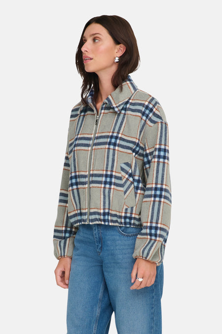 Veste courte multicolore de ONLY, à carreaux avec fermeture éclair, portée avec un jean et des boucles d'oreilles argentées.