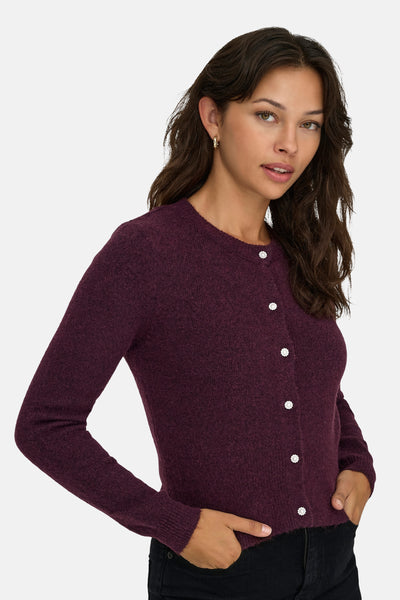 Cardigan bordeaux en maille ONLY, avec des boutons décoratifs et porté avec un jean noir.
