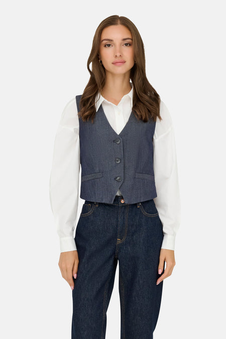Donkerblauwe spijkerblazer van JDY, gedragen over een wit overhemd met lange mouwen en een donkerblauwe broek.