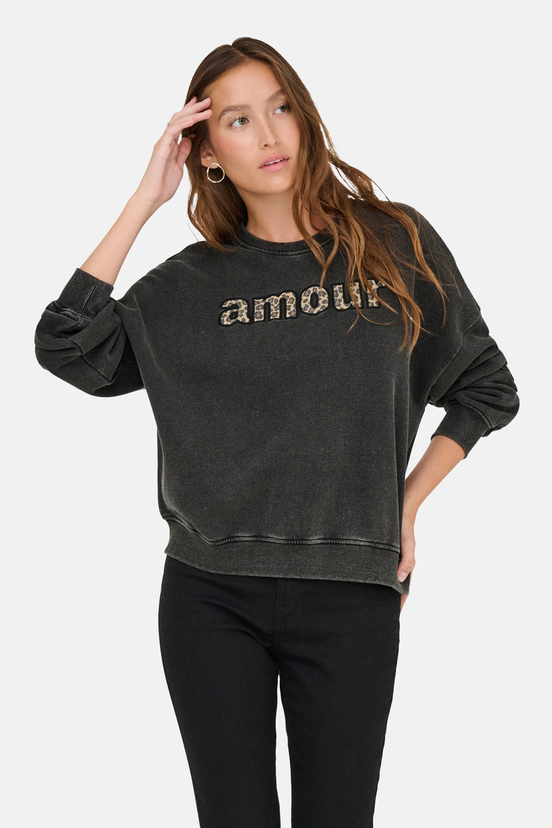 Zwarte rondehals sweatshirt van ONLY, met luipaardprint op de voorkant, gedragen met een zwarte broek.