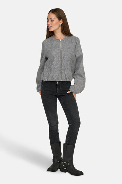 Korte grijze jas van JDY, met ritssluiting, gedragen met een zwarte jeans en laarzen.