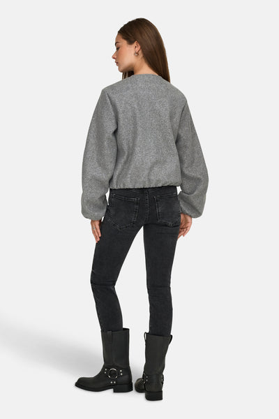 Korte grijze jas van JDY met lange pofmouwen, gedragen met een zwarte jeans en laarzen.