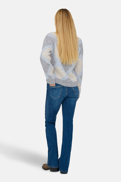 Multikleuren V-hals trui van JDY, met ruitpatroon op een gemêleerde achtergrond, gedragen met een blauwe jeans.