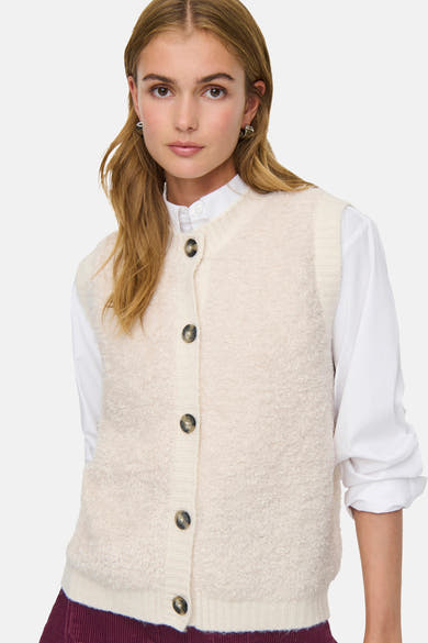 Débardeur écru de JDY avec une texture bouclée, porté sur une chemise blanche à manches longues.
