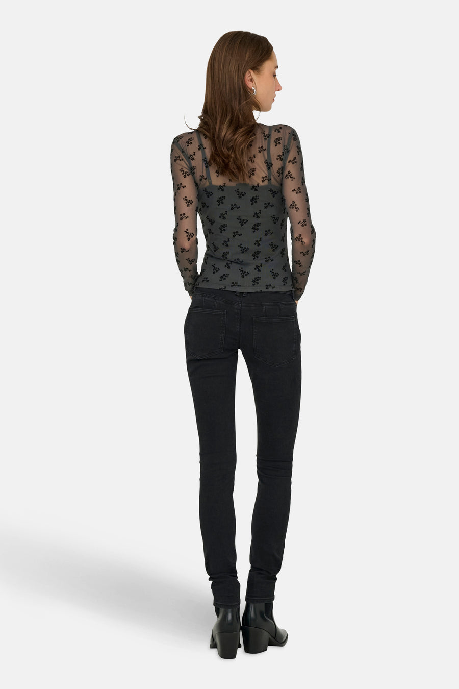 Grijze T-shirt met lange mouwen van JDY, met zwarte bloemenprints op een top met spaghettibandjes, gedragen met een zwarte jeans.