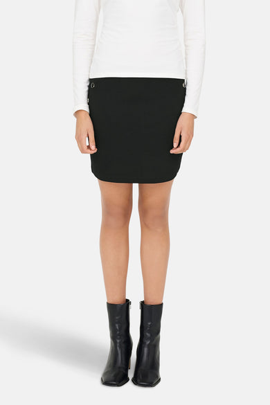 Zwarte korte rok van JDY, met knoopdetails en gedragen met een witte top en zwarte laarzen.