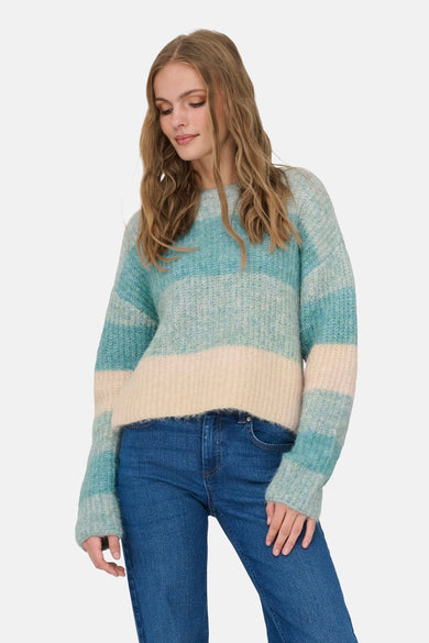 Pull col rond bleu de JDY, à rayures turquoise et crème, porté avec un jean en denim.
