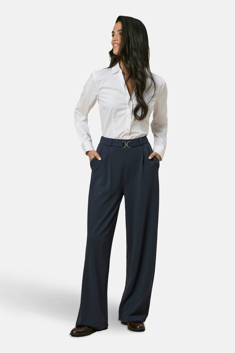 Zwarte broek JDY, wijde pasvorm met hoge taille en een gouden gespceintuur, gedragen met een wit overhemd.