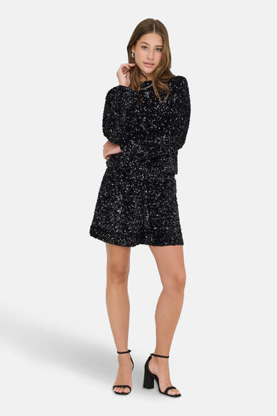 Jupe courte noire scintillante de ONLY, avec des paillettes sur toute la surface et des chaussures à talons noirs.
