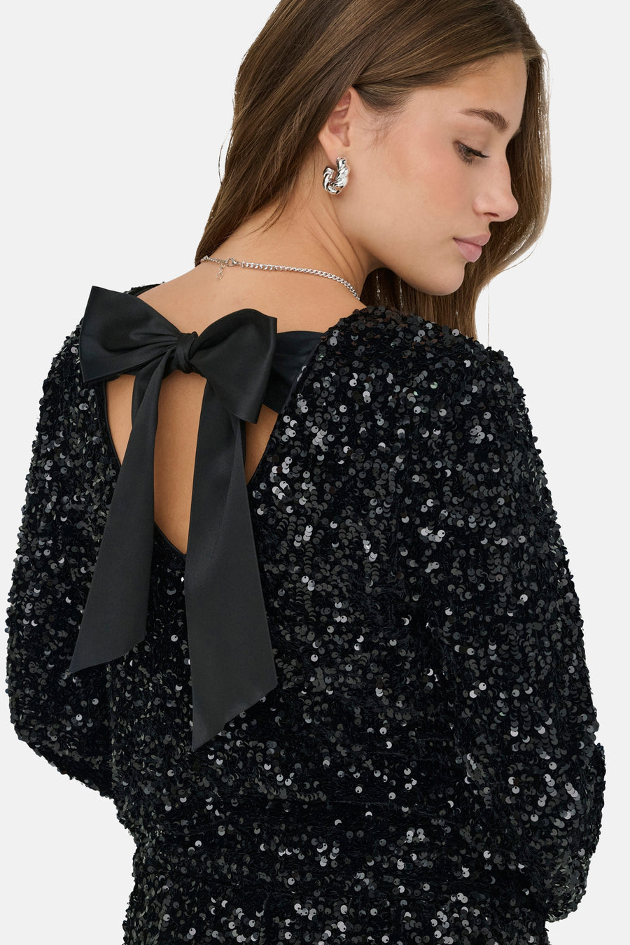 Zwarte blouse met lange mouwen van ONLY, met blote rug en grote decoratieve strik, gedragen met een zilveren ketting.