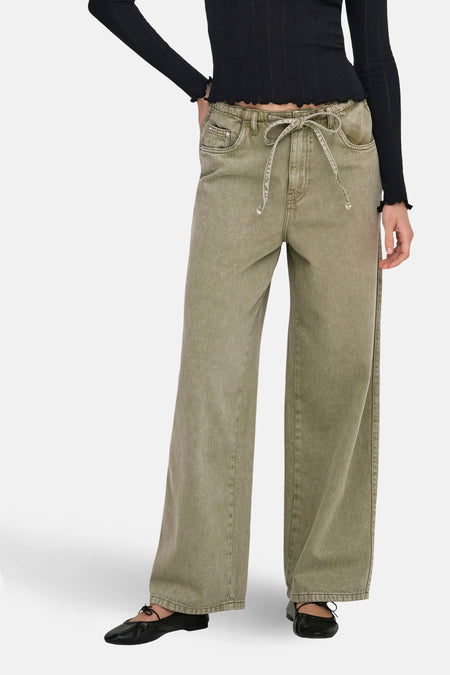 Jeans coloré kaki by ONLY, avec une ceinture à nouer et porté avec un haut noir.
