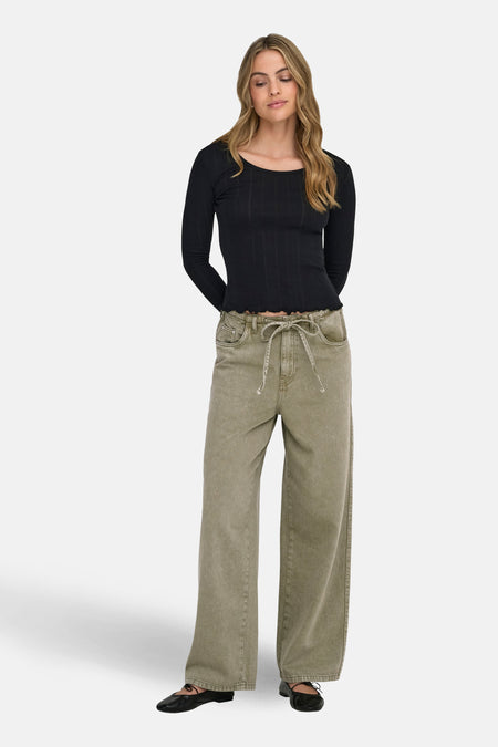 Jean coloré kaki de ONLY, avec cordon de serrage et jambes larges, porté avec un haut noir et des ballerines.