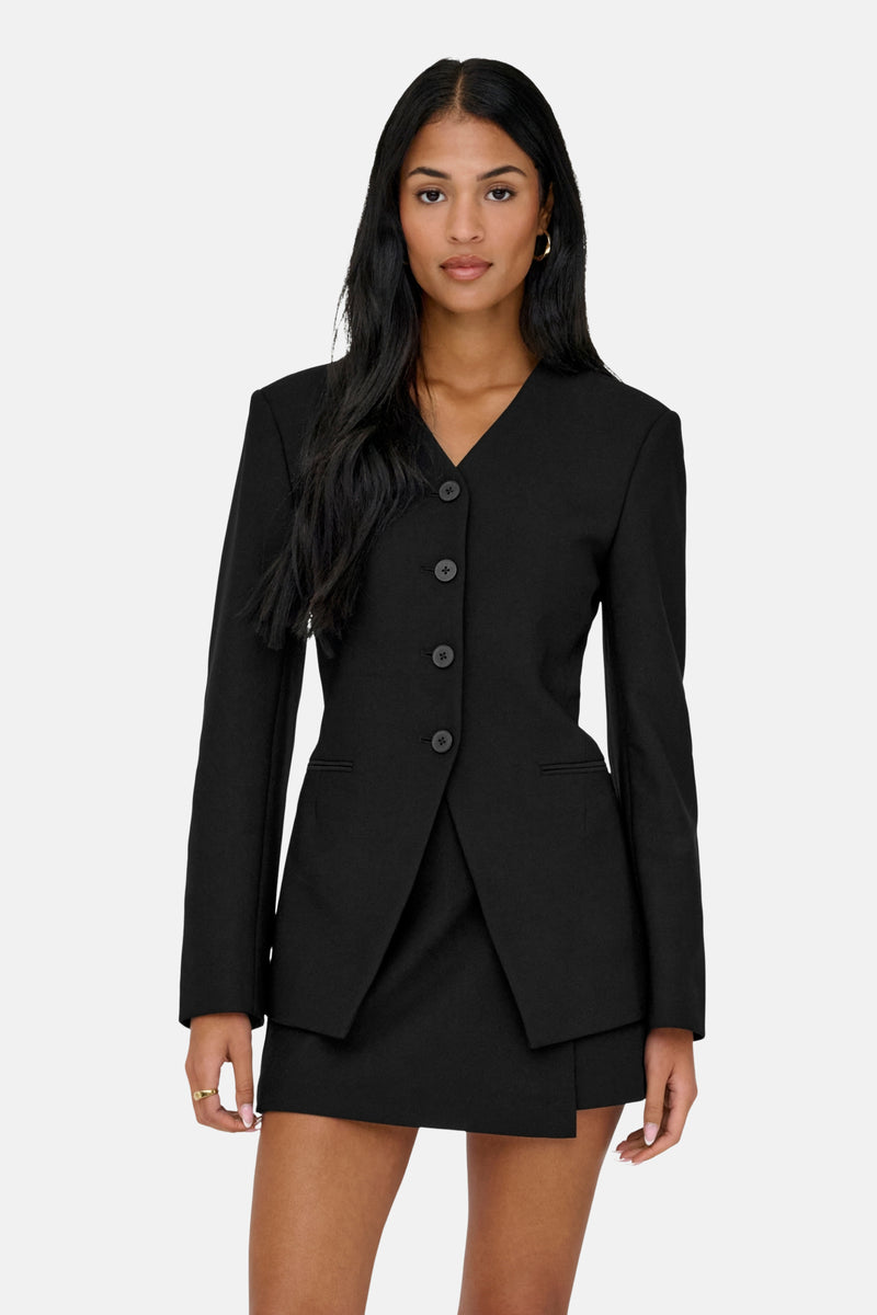 Blazer noir by ONLY, avec une coupe ajustée et une fermeture à quatre boutons, porté avec une minijupe noire.