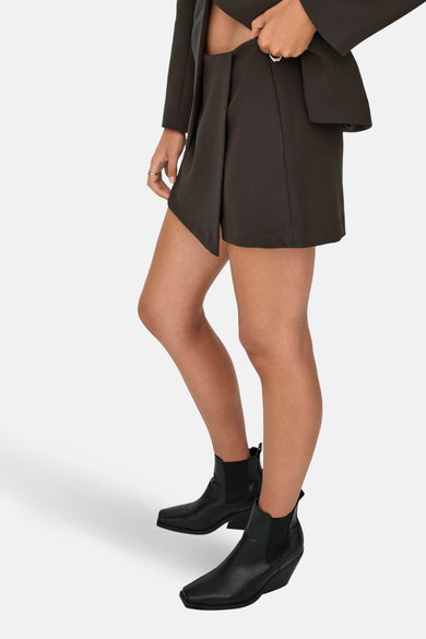 Bruine skort van ONLY met wikkelmodel, gedragen met een bijpassende blazer en zwarte leren enkellaarsjes.