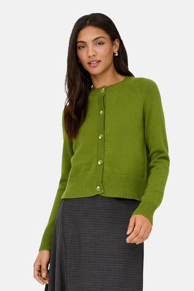 Groene gebreide cardigan van ONLY®, gedragen met een asymmetrische gestreepte rok en zwarte schoenen.