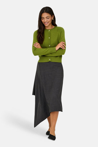 Cardigan vert en maille ONLY®, porté avec une jupe à rayures asymétrique et des chaussures noires.
