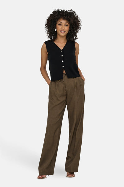 Zwart gilet van JDY met knopen, gedragen met een bruine pantalon met plooien en sandalen.
