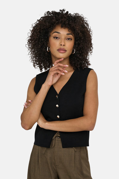 Gilet noir de JDY avec boutons dorés, porté sur un pantalon marron à taille froncée.