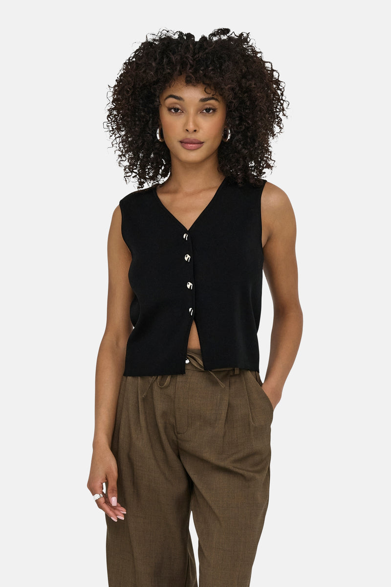 Zwarte bodywarmer van JDY met zilveren knopen, gedragen met een bruine broek met trekkoord.