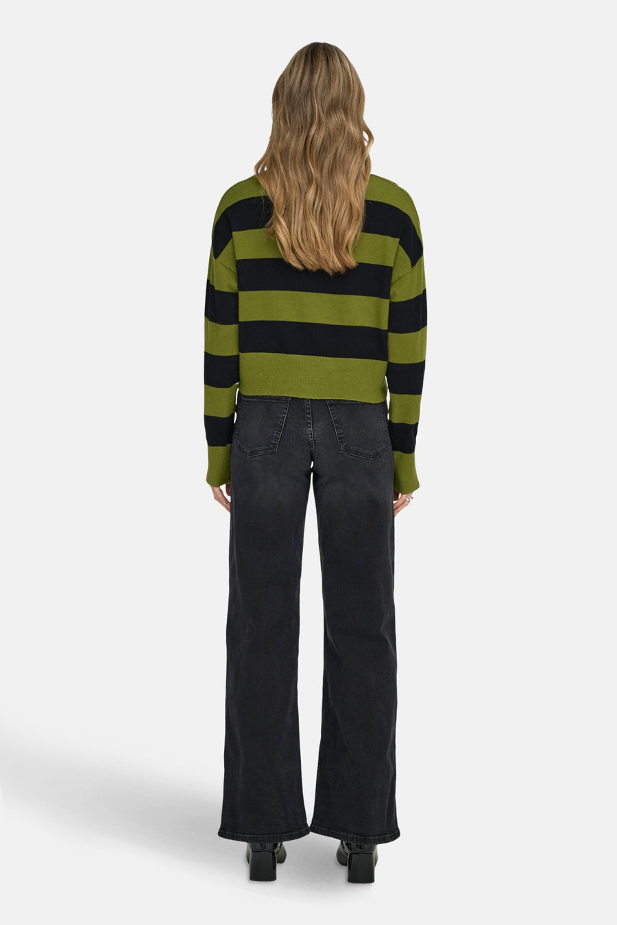 Groene trui met zwarte strepen van ONLY, gedragen met een wijde zwarte jeans en zwarte hakken.
