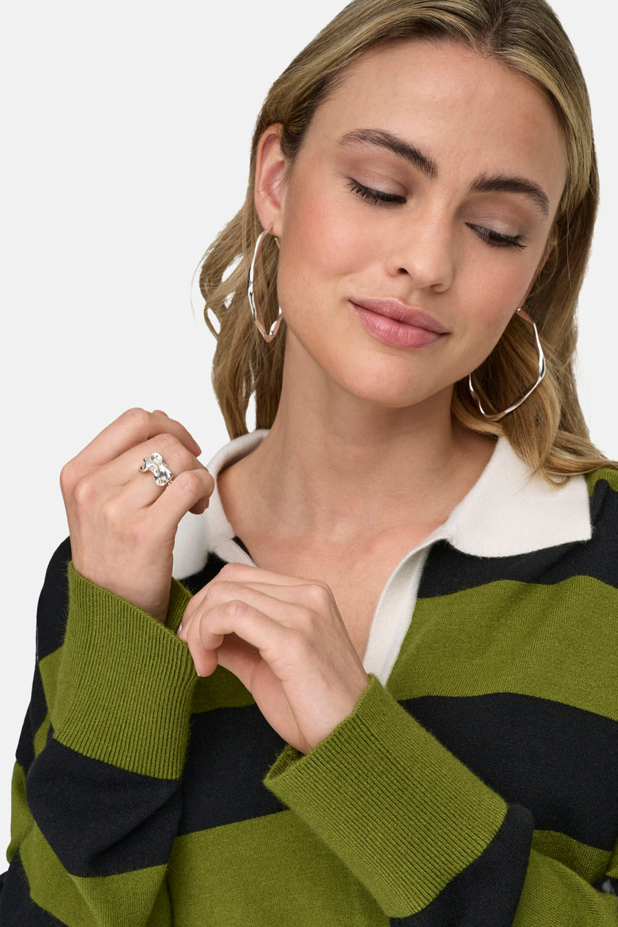 Groene gestreepte trui van ONLY, gedragen met zilveren oorringen en een gestreept poloshirt.