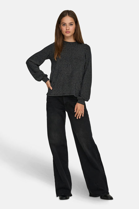 Blouse noire à manches longues de ONLY®, avec un motif texturé et portée avec un jean noir taille haute.
