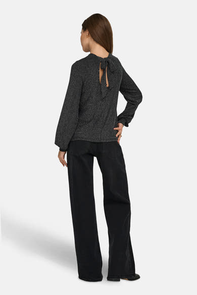 Zwarte blouse met lange mouwen van ONLY, met een decoratieve strik op de rug, gedragen met een wijde zwarte broek.