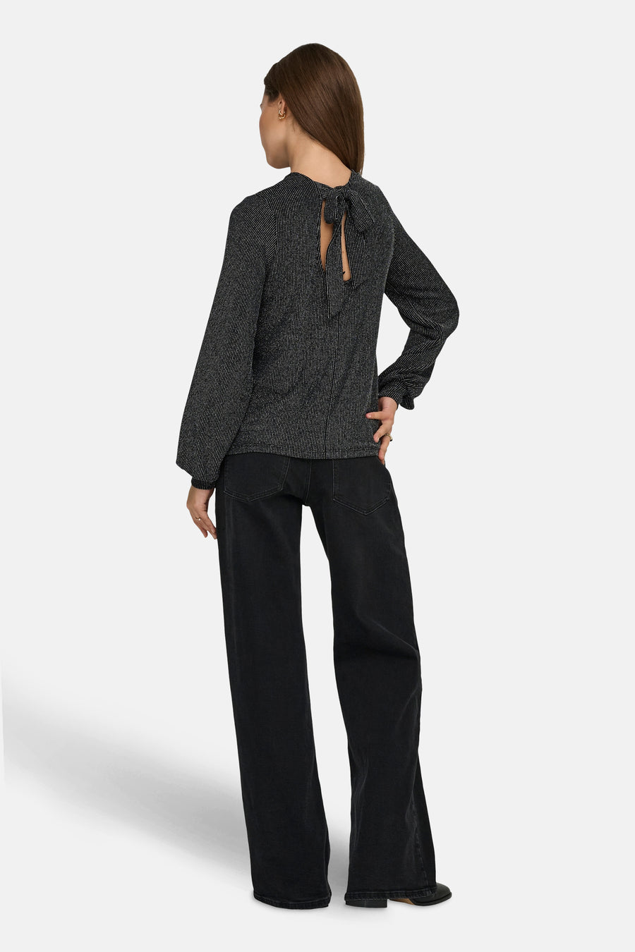 Zwarte blouse met lange mouwen van ONLY, met een decoratieve strik op de rug, gedragen met een wijde zwarte broek.