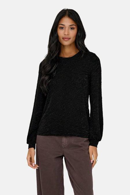 Zwart blouse met lange mouwen van ONLY, met subtiele textuur, gedragen met een bruine broek en zwarte enkellaarsjes.