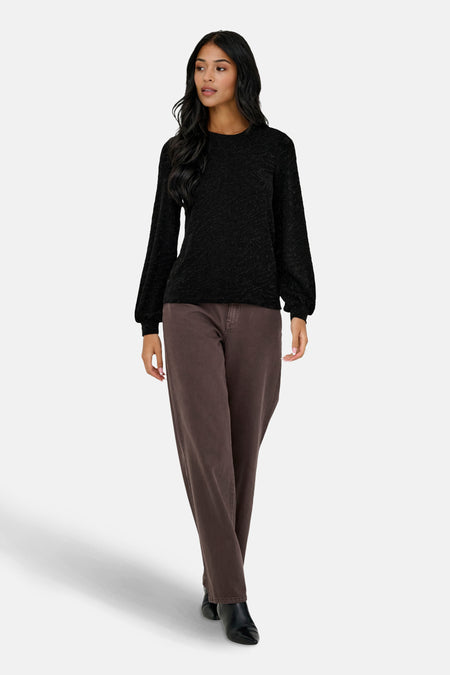 Blouse noire à manches longues de ONLY, à texture subtile, portée avec un pantalon marron et des bottines noires.
