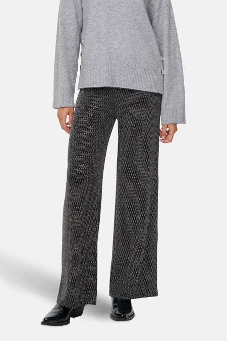 Zwarte broek met geometrische patronen van ONLY, gedragen met een grijze trui en zwarte schoenen.