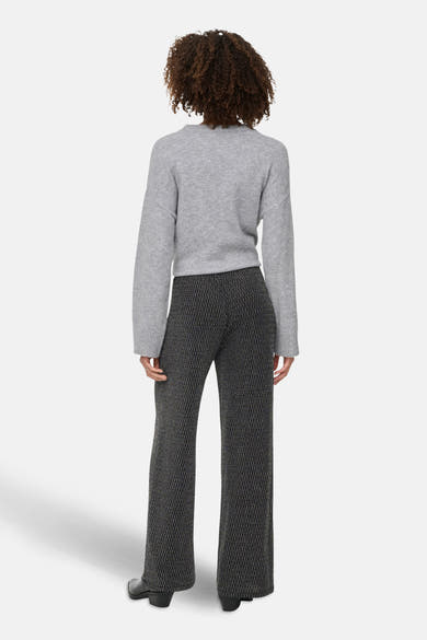 Zwarte broek met geometrisch patroon van ONLY, gedragen met een grijze trui met lange mouwen en zwarte enkellaarsjes.