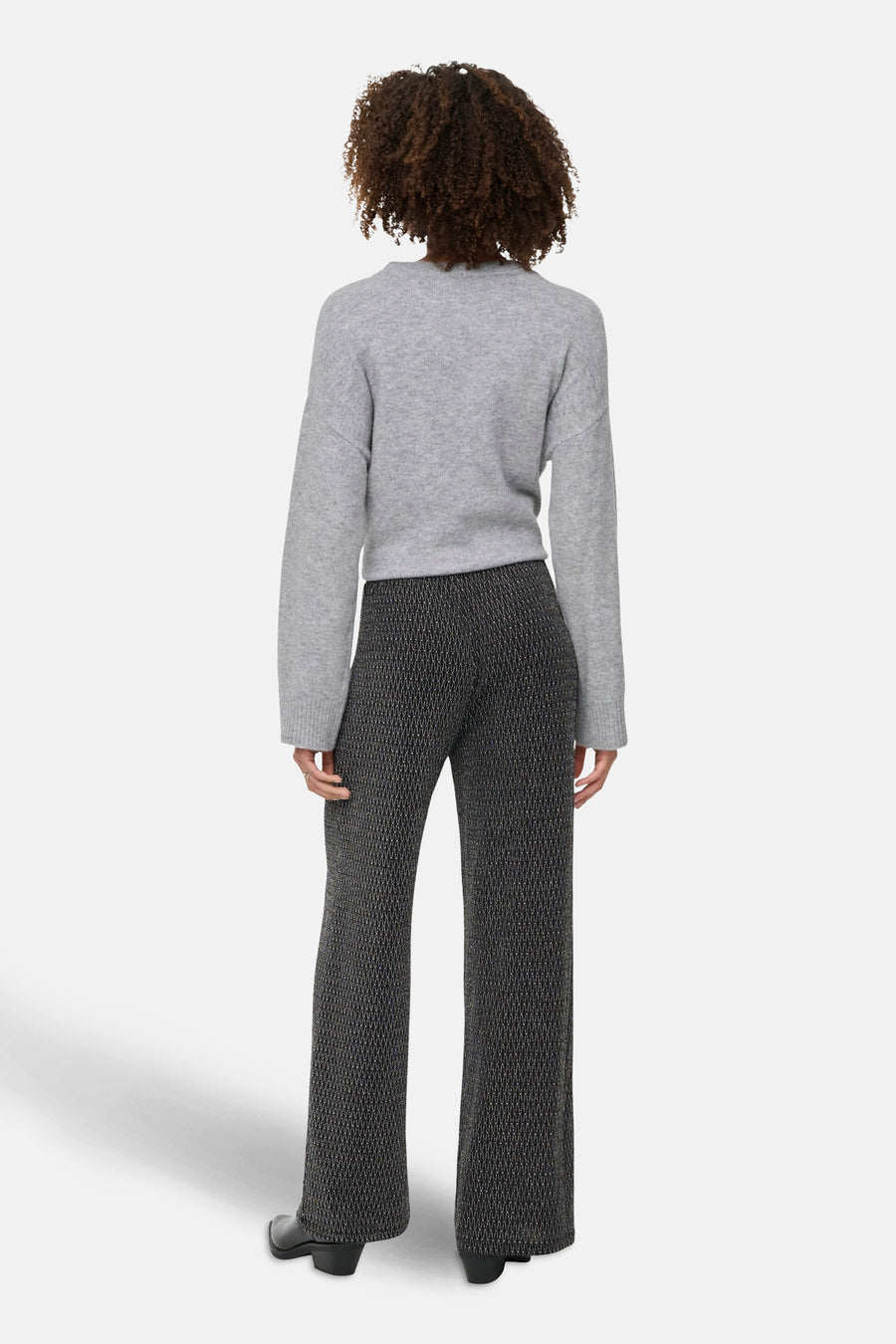 Zwarte broek met geometrisch patroon van ONLY, gedragen met een grijze trui met lange mouwen en zwarte enkellaarsjes.