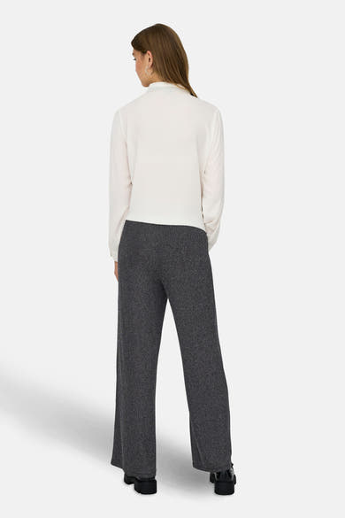 Zwarte broek met glinsterende strepen van ONLY, gedragen met een witte blouse met lange mouwen en zwarte schoenen.