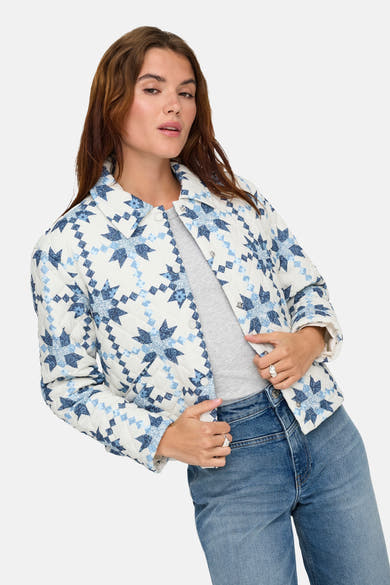 Korte meerkleurige jas van ONLY®, met sterrenpatroon en gewatteerd, gedragen met een grijs T-shirt en een blauwe jeans.