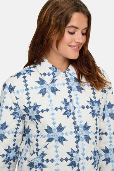 Korte meerkleurige jas van ONLY, met blauw en wit sterrenpatroon, gedragen met kastanjebruin haar.