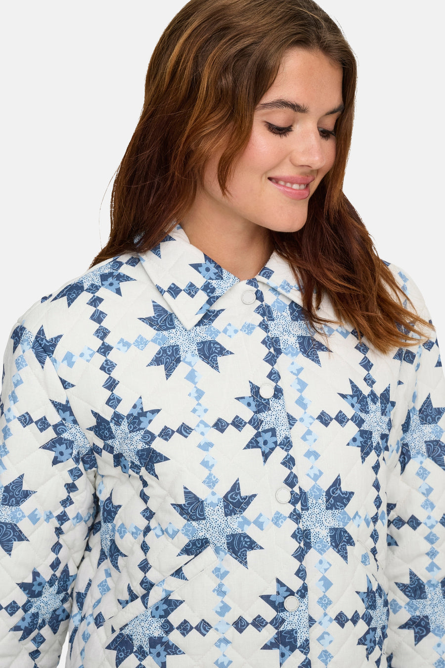 Korte meerkleurige jas van ONLY, met blauw en wit sterrenpatroon, gedragen met kastanjebruin haar.