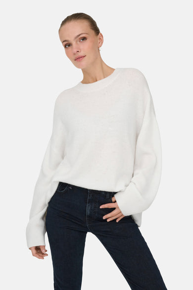 Pull à col rond blanc de JDY, porté avec un jean bleu foncé.