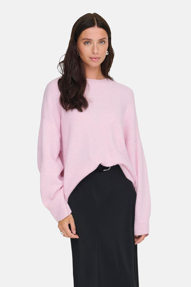 Pull rose à col rond de JDY, porté avec une jupe noire et des boucles d'oreilles argentées.
