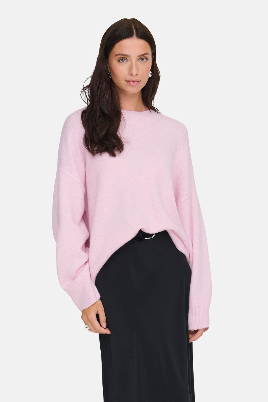 Pull rose à col rond de JDY, porté avec une jupe noire et des boucles d'oreilles argentées.
