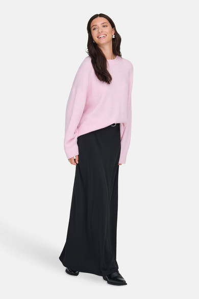 Pull rose à col rond de JDY, porté avec une longue jupe noire et des bottines noires.