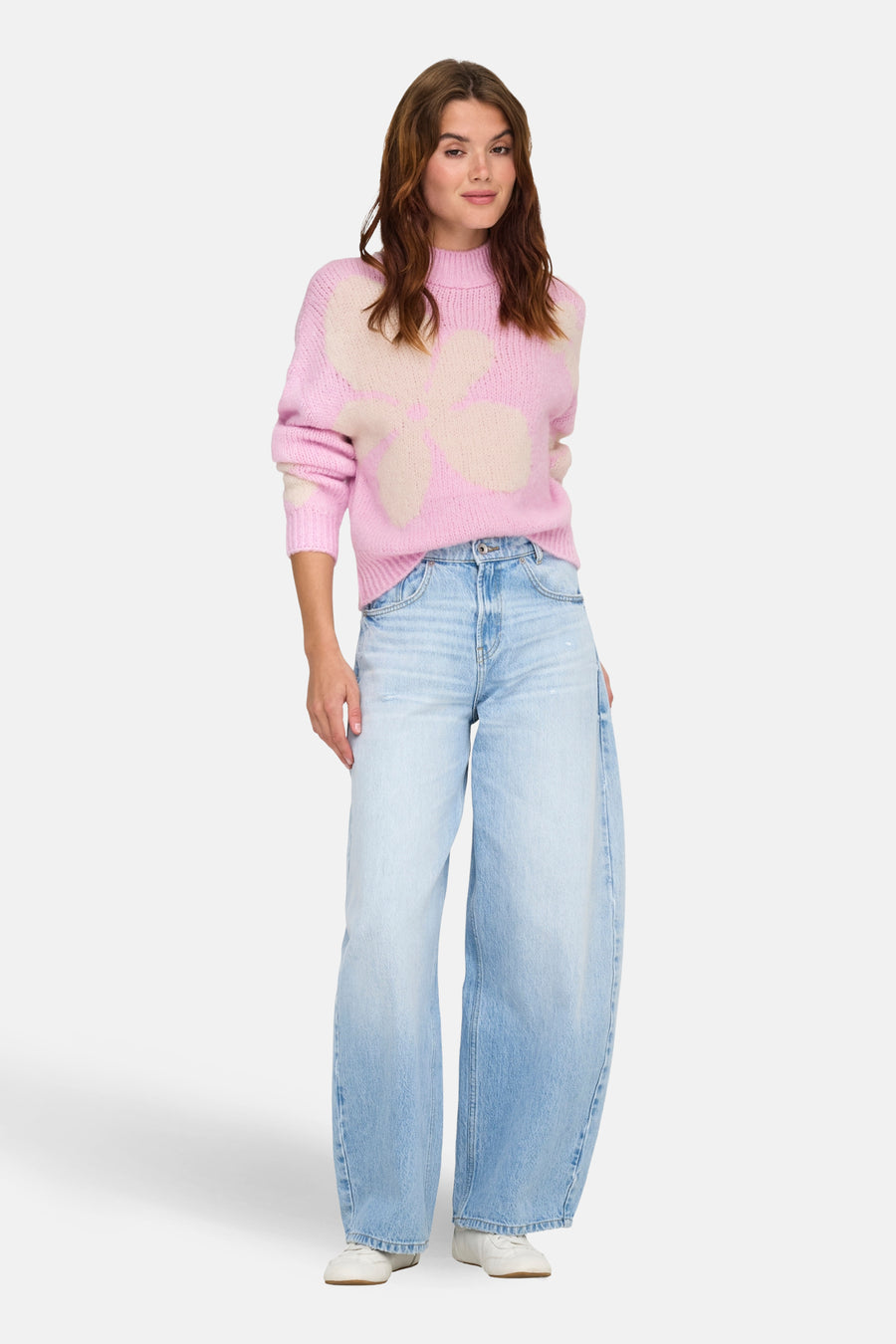 Pull à col roulé rose de JDY avec motif floral et porté avec un jean ample bleu.
