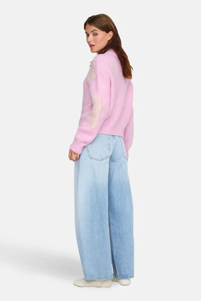 Roze coltrui van JDY, met bloemenpatroon op de mouwen, gedragen met een wijde jeans en witte schoenen.