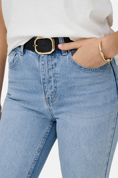 Lichtblauwe Mom jeans van ONLY, gedragen met een zwarte riem met gouden gesp en een gouden armband.